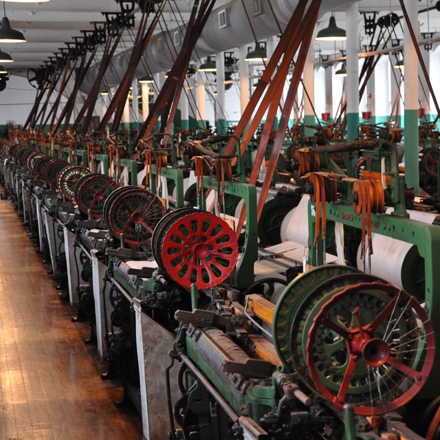 room filled with dozens of old wooden textile mill machines