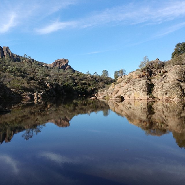 lake surrounded by colorful trees and tall rocks, with their reflection on the water