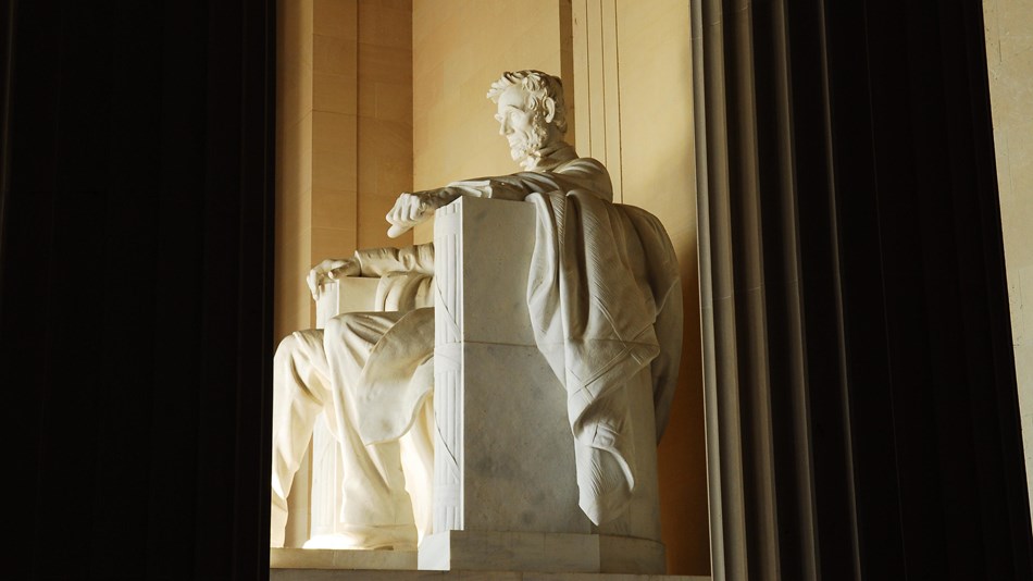 Statue of Abraham Lincoln seated and framed by two massive columns 