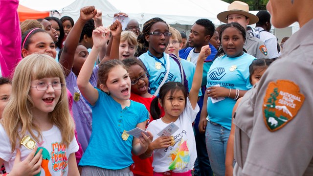 Group of kids wearing Junior Ranger badges holding hand up to take the Junior Ranger pledge