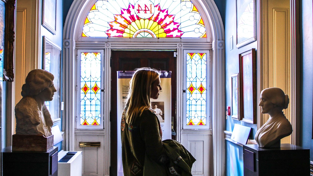 Visitor looking at a bust of a suffragist in a hallway