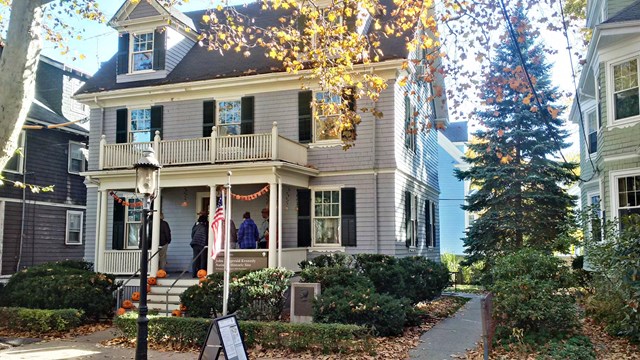 Three-story light blue house decorated with visitors on the porch