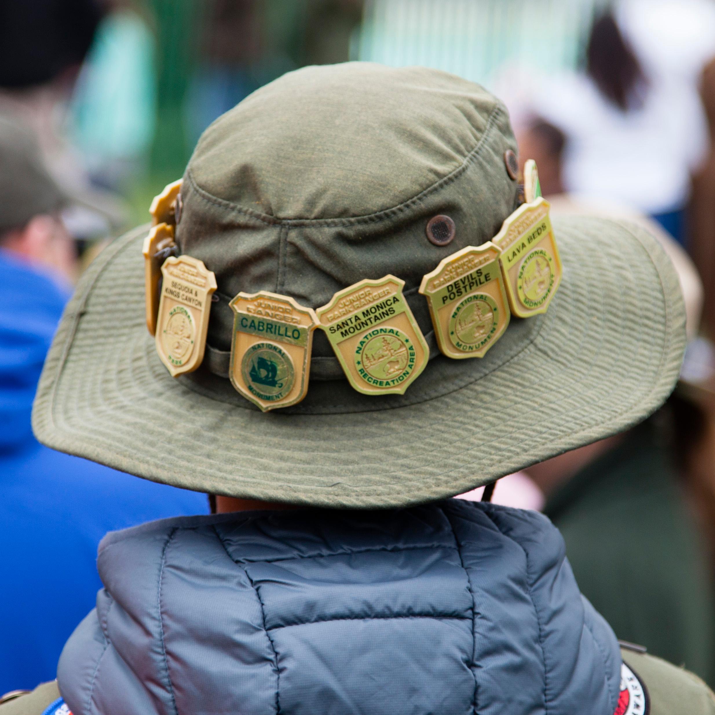 Back of a kid's hat covered with Junior Ranger badges