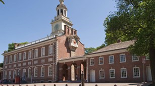 Color photo of Independence Hall, a two story red brick building with bell tower.