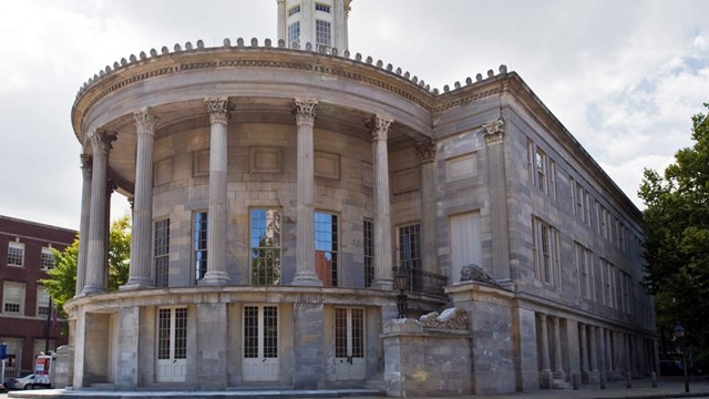 Color photo of a Greek Revival building with semicircular columned facade at the building's rear.