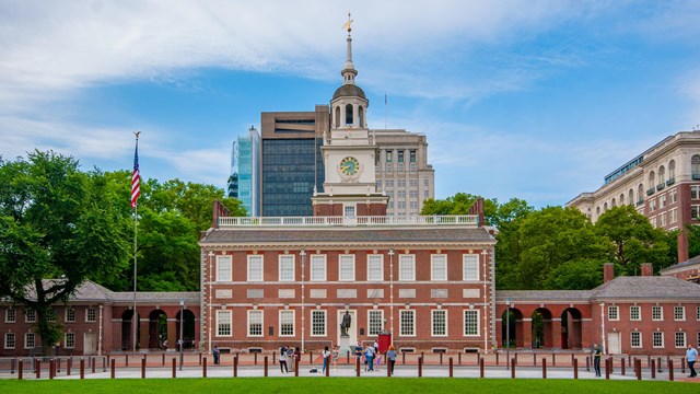 Two-story red brick colonial building with white clock and bell tower.