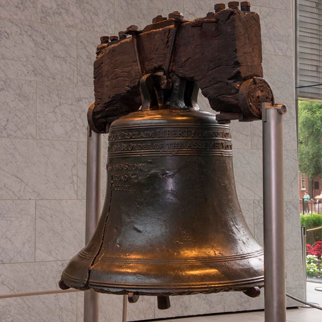Color photo of the Liberty Bell, a bronze bell with wooden yoke.