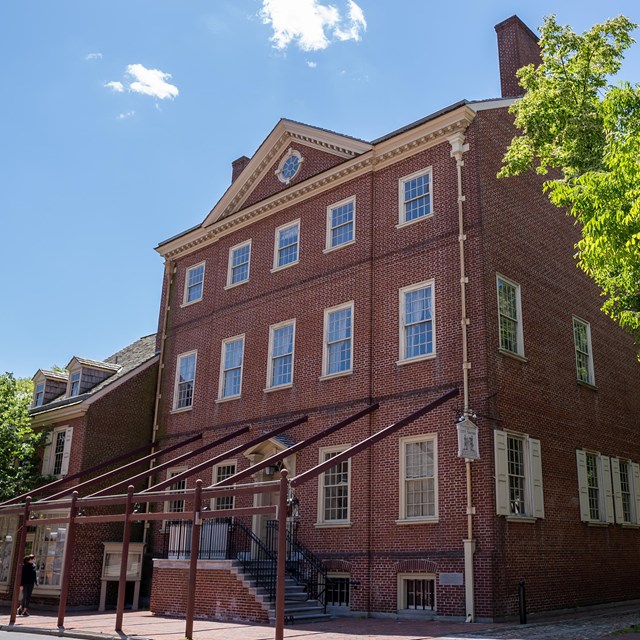 Exterior view of three story red brick building with numerous windows on each level.