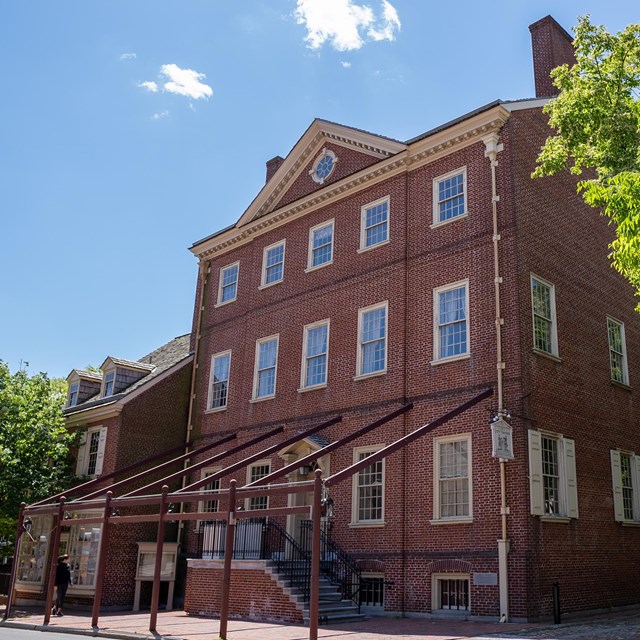 Exterior view of three story red brick building with numerous windows on each level.