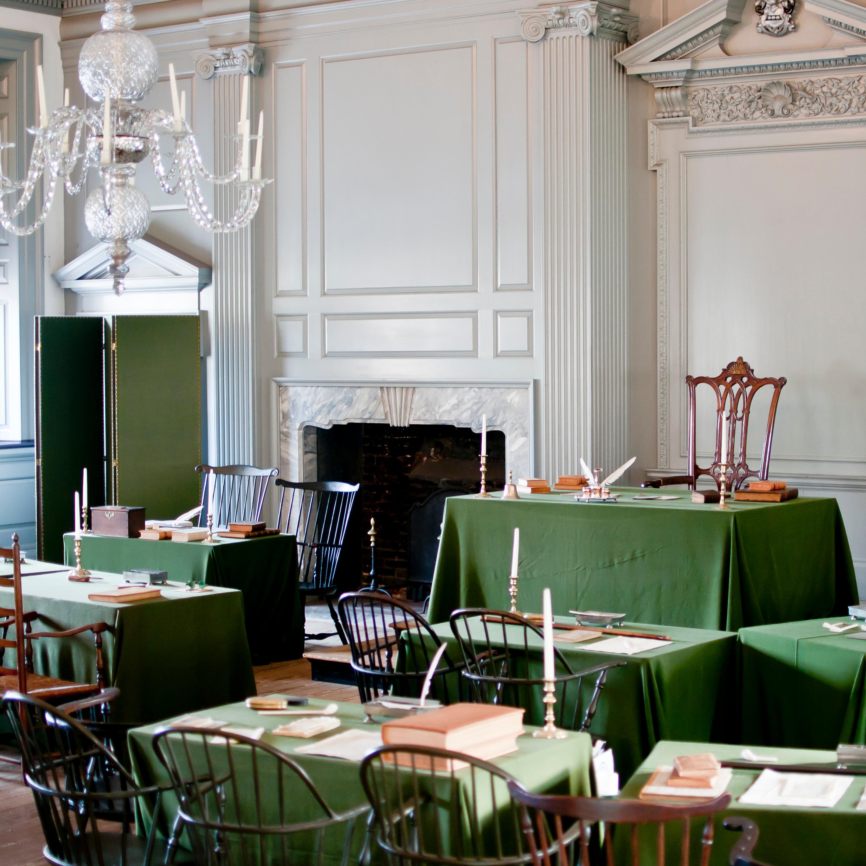 Color photo of Assembly Room with green cloth-covered tables facing a single table up front.