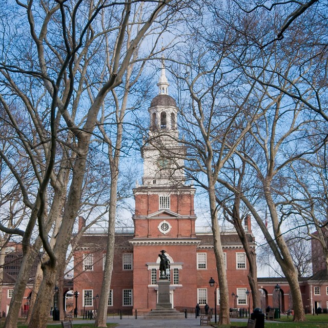 Two story, red-brick building with white clock and bell tower. 