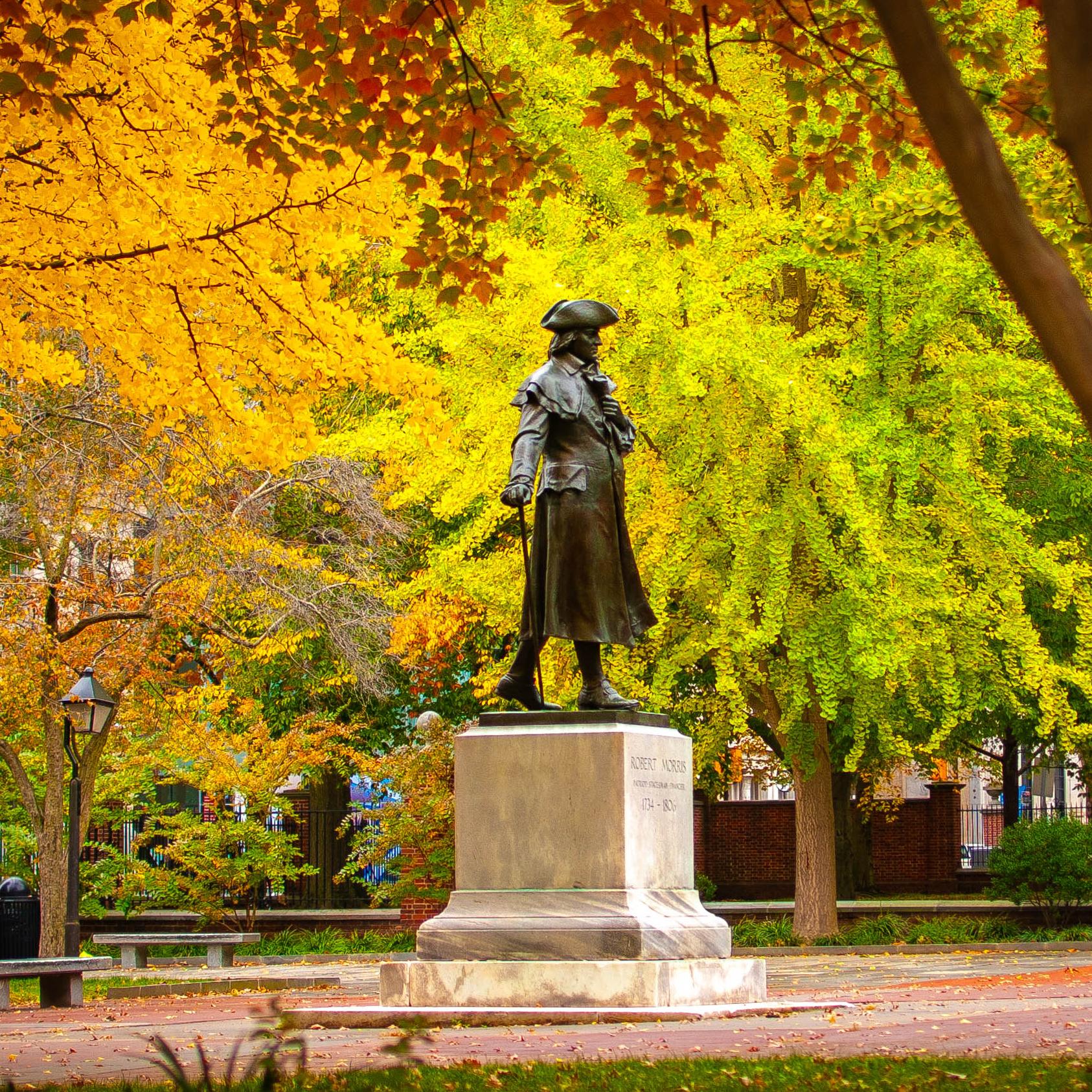 statue of a man on a pedestal surrounded by deciduous trees