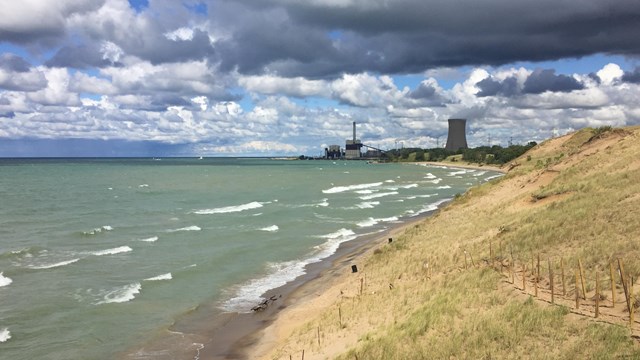 Grass covered dune overlooking a turbulent Lake Michigan with Michigan City's generating tower.  