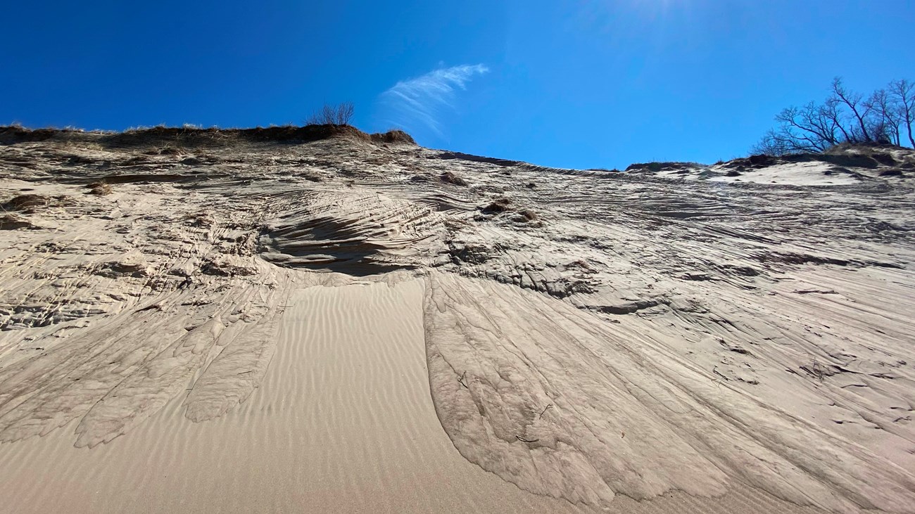 View of dune with blue sky with bright sun above the high, eroded along Lake Michigan's shore.