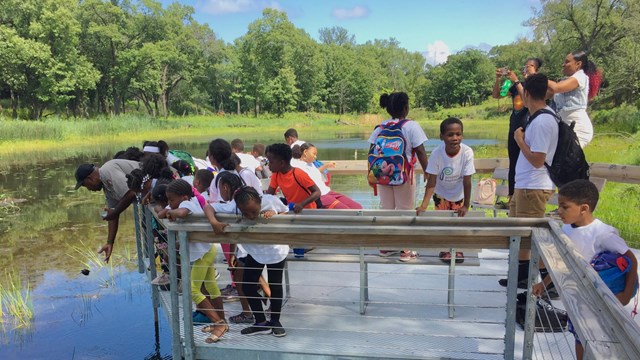 National Park Service ranger on a boardwalk over water surrounded by students.