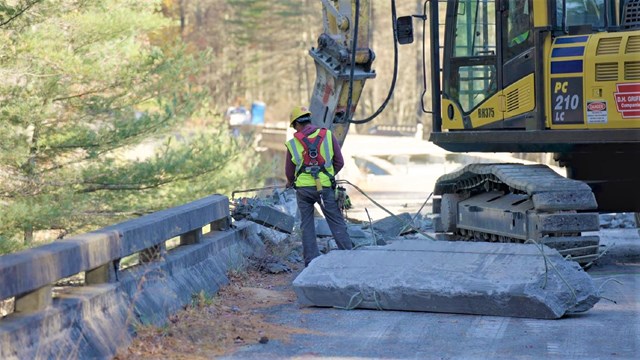 Construction worker lowering a line off a bridge