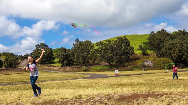 Kids running with kites in a grass field