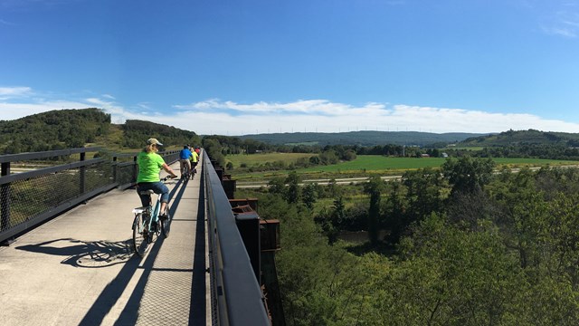 Bicyclists on a bridge overlooking a valley 