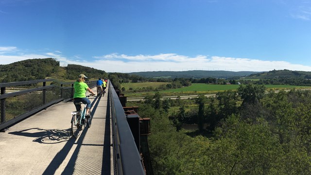 Bicyclists on a bridge overlooking a valley