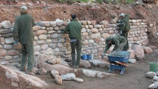 Trail crew working on a vertical stone wall