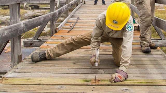 Trail crew fixing nails on a boardwalk 