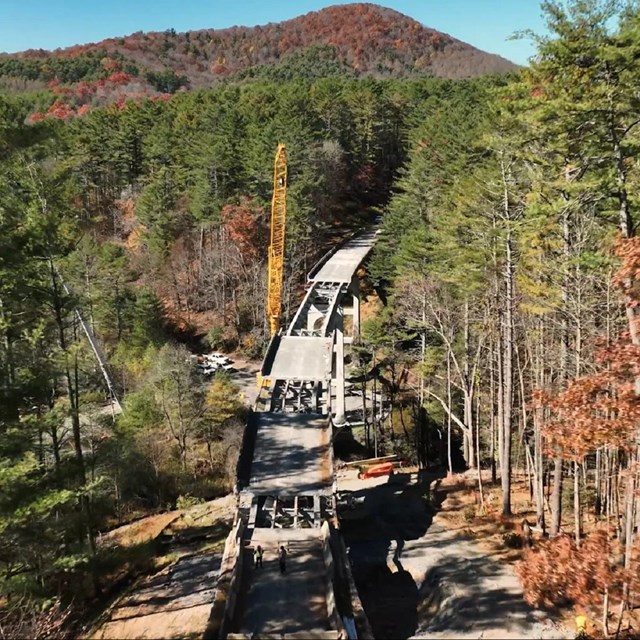 Construction crews and a large crane on a bridge under construction 