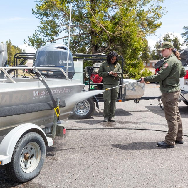 a person power washes a boat on a trailer