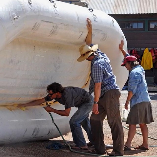 three people clean an inflatable raft