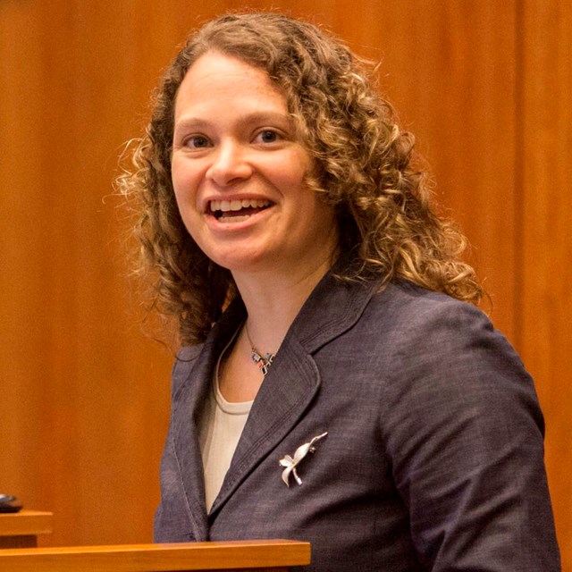 Woman standing at podium talking into microphone,