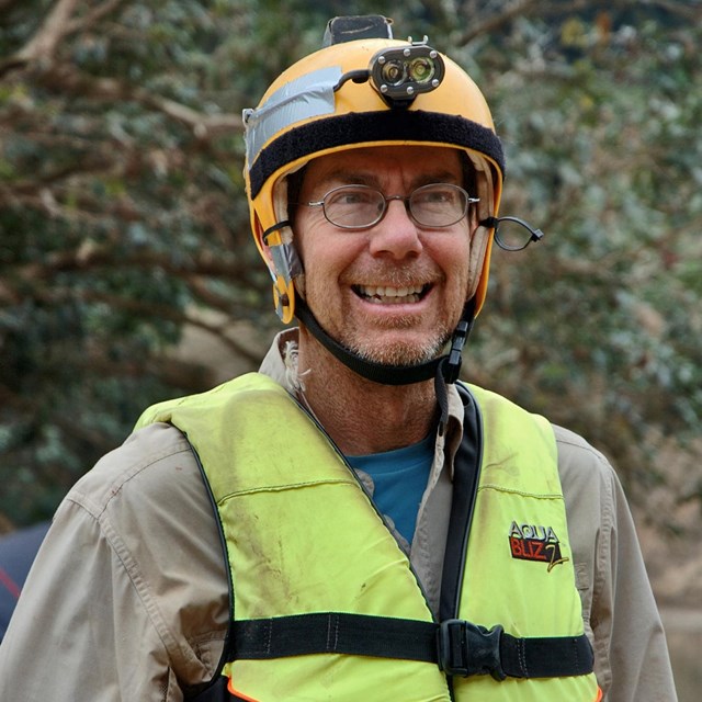 Man with life jacket and helmet with light.