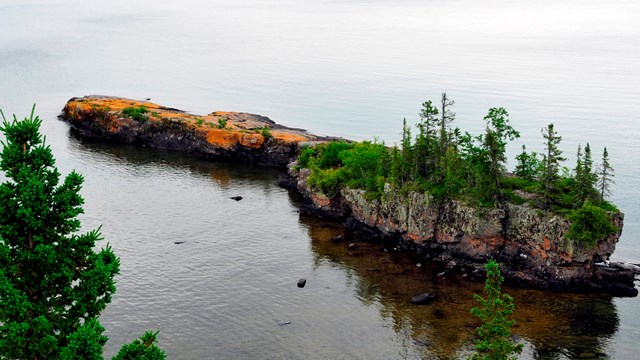 View of one of Isle Royale's small islands dotted with evergreens and rocky shoreline from above.