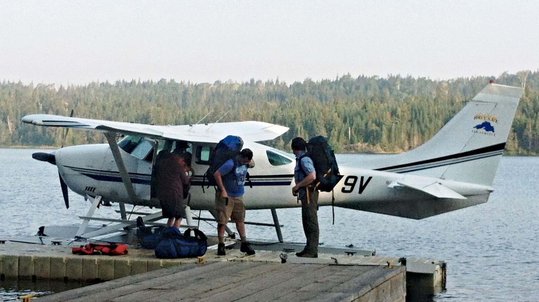 A white and red seaplane sits parked on a floating dock.
