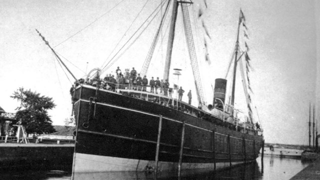ship with large, celebratory crowd on top deck