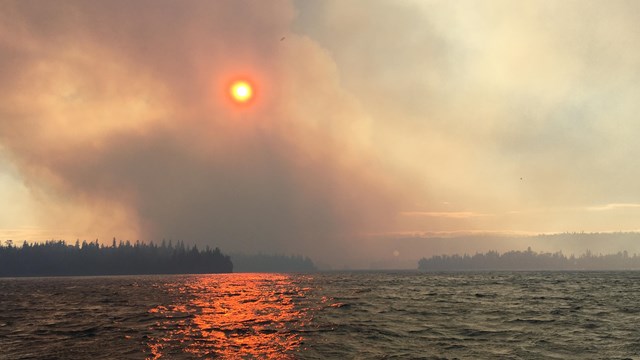 Smoke rises from Isle Royale. The sky is orange. 