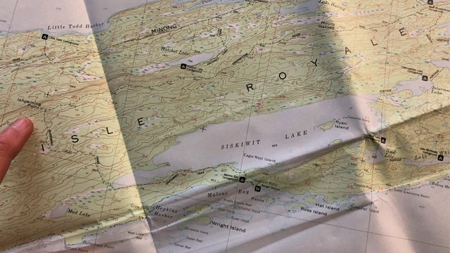 A hand points to a map of Isle Royale National Park.