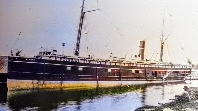 SS Algoma docked with a man looking on, sitting on shore