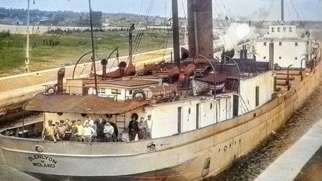 view of SS Glenlyon docked with crew posed on the bow for photo