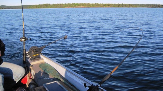 A boat in the water with fishing poles out 