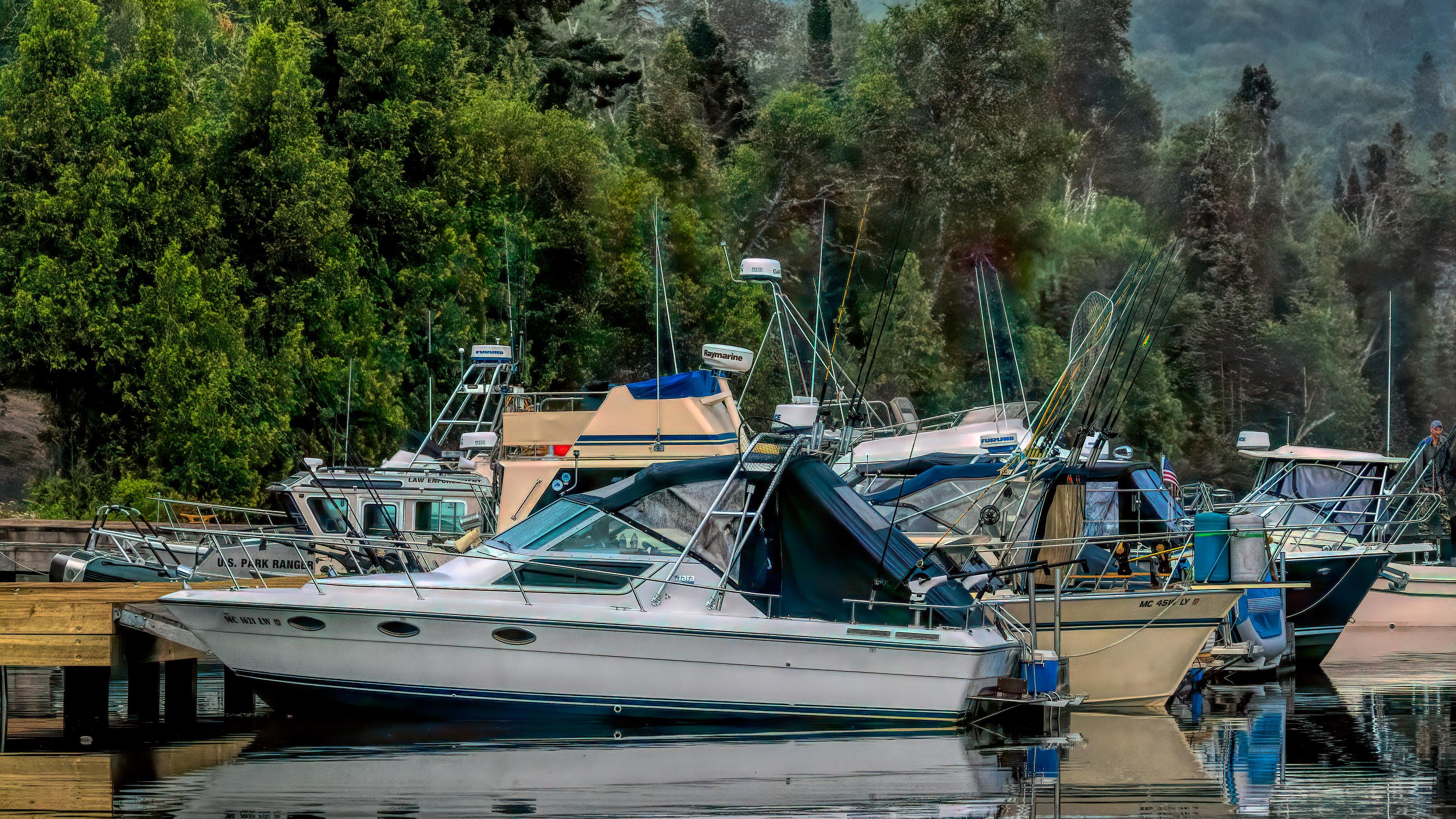 A red sailboat is tied to a dock with an island in the background and water.