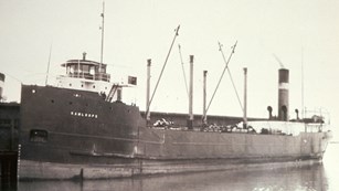 SS Kamloops docked next to short, flat building