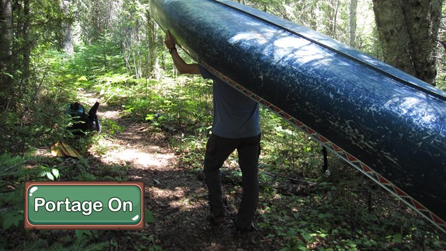 A person carries a blue canoe above their head.