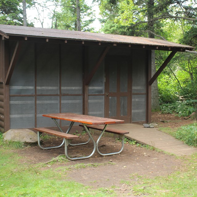 Campground shelter with picnic table and ramp at Daisy Farm Campground at Isle Royale. 