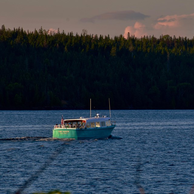 A teal colored boat underway in a large channel.