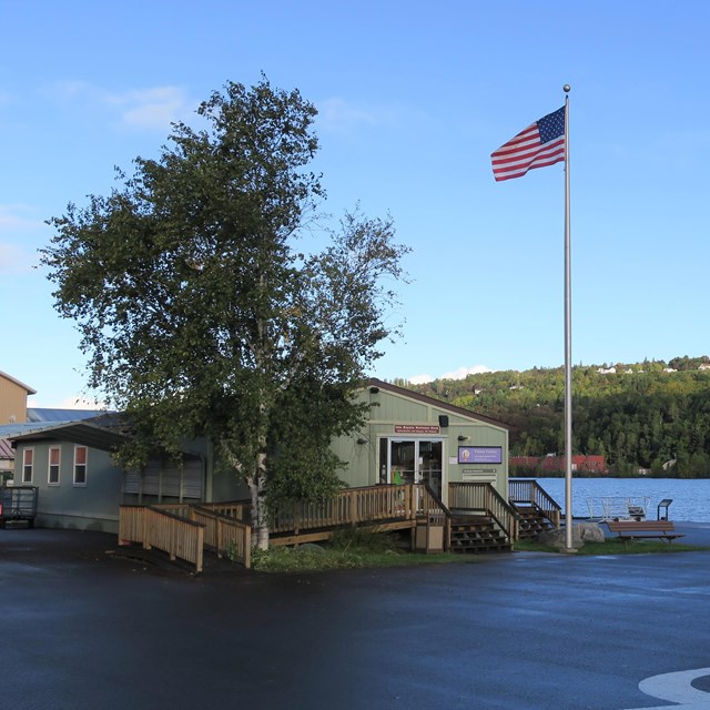 Isle Royale's mainland visitor center on a clear day with the American flag blowing in the wind.