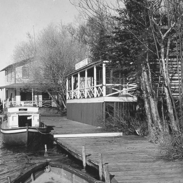 lodge with front porch lakeside, boat docked in front