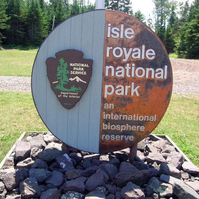 Isle Royale National Park international biosphere reserve sign in an open grass area.