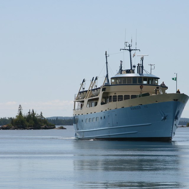 Passenger ferry the Ranger III in the waters of Isle Royale, next to a small island.