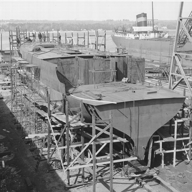 B&W photo of RANGER III in drydock construction. Scaffolding surrounds the half-built boat.