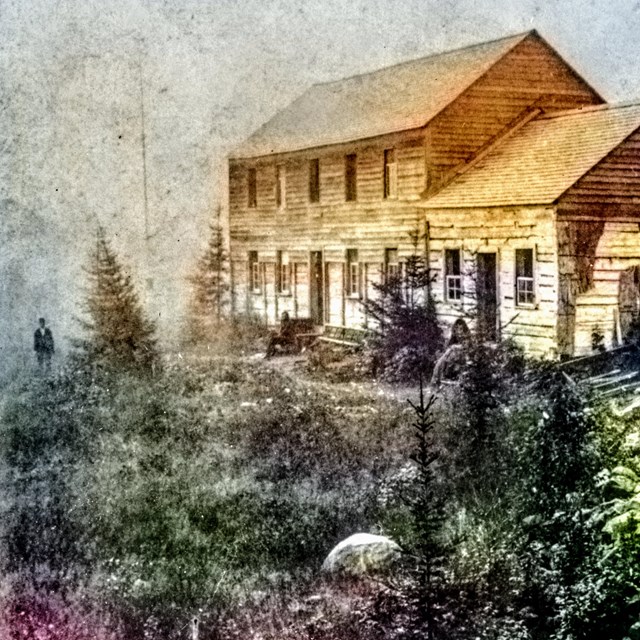 the two story Siskiwit Mine company buiding, with a man sitting out front