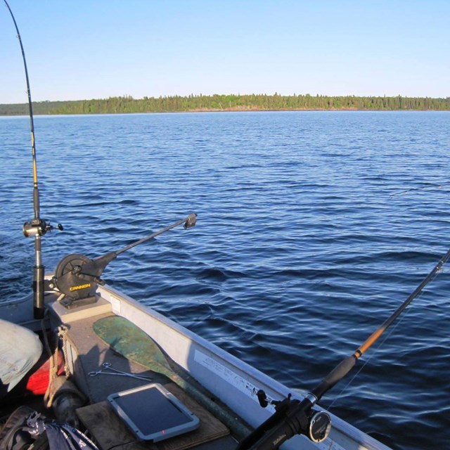 A boat in the water with fishing poles out 